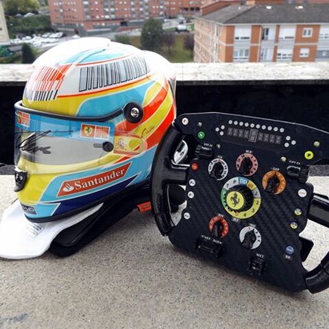 Beautiful picture of a mini f1 replica helmet signed by fernando alonso and a replica f1 steering wheel of their time in ferrari f1 team.